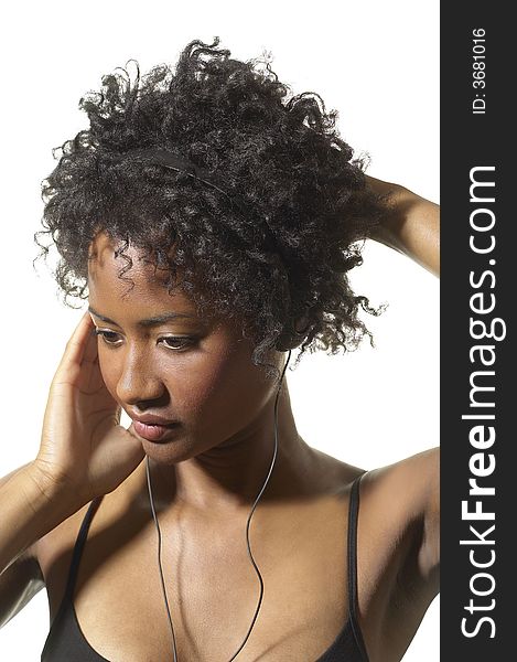 African American woman holds her music head phones and just the head phone against her ear. African American woman holds her music head phones and just the head phone against her ear.