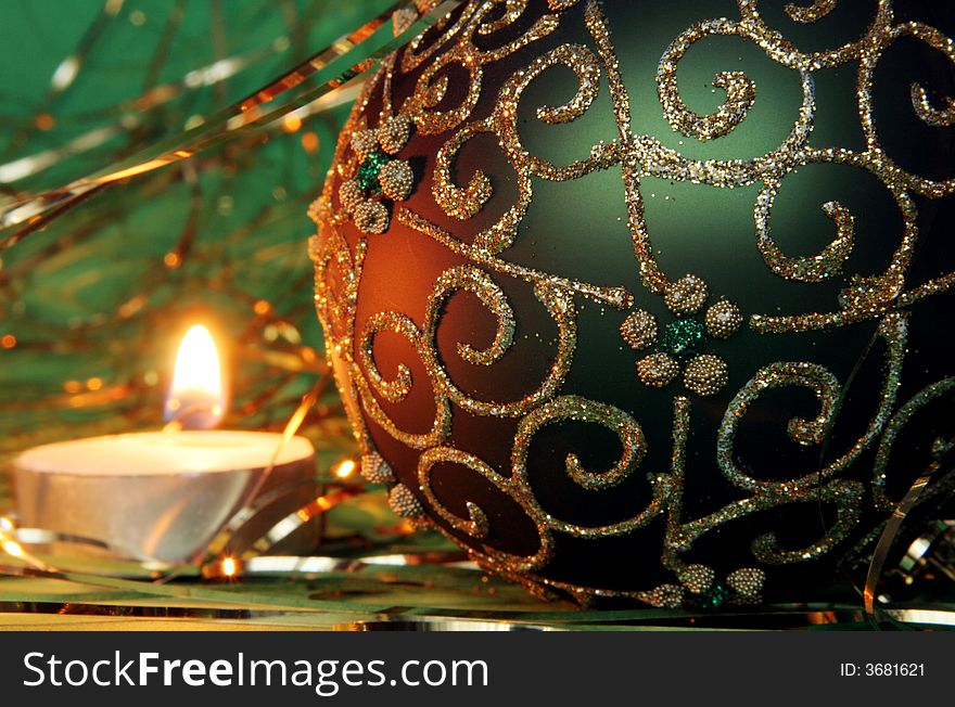 Christmas candle and ball with gold ornament on a green background. Christmas candle and ball with gold ornament on a green background
