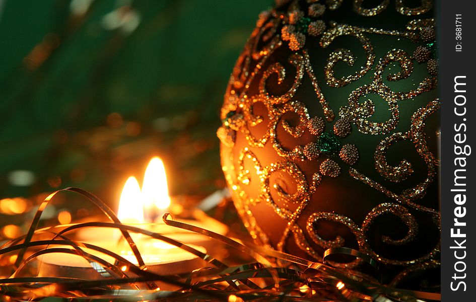 Christmas candles and ball with gold ornament on a green background. Christmas candles and ball with gold ornament on a green background.