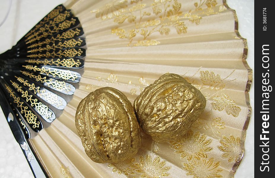 Two golden walnuts on japanese brocade fan. Two golden walnuts on japanese brocade fan