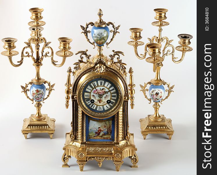 An antique clock with floral decor and painted enamel. Two sconces are in the suit. An antique clock with floral decor and painted enamel. Two sconces are in the suit.