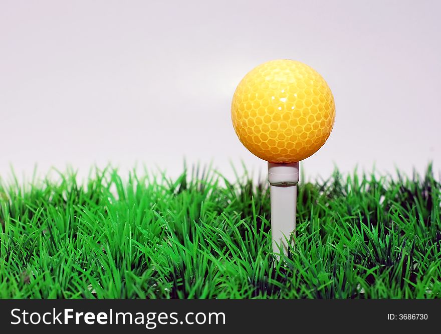 Yellow golfball in orange tee, green fairway, isolated on black background. Yellow golfball in orange tee, green fairway, isolated on black background
