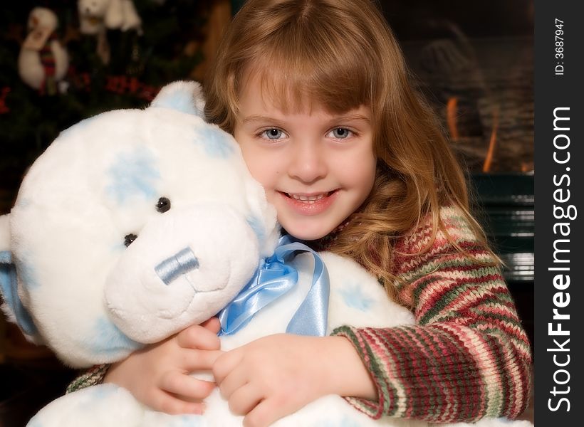 Young elementary girl hugging a giant blue and white Teddy bear at Christmas time. Young elementary girl hugging a giant blue and white Teddy bear at Christmas time.