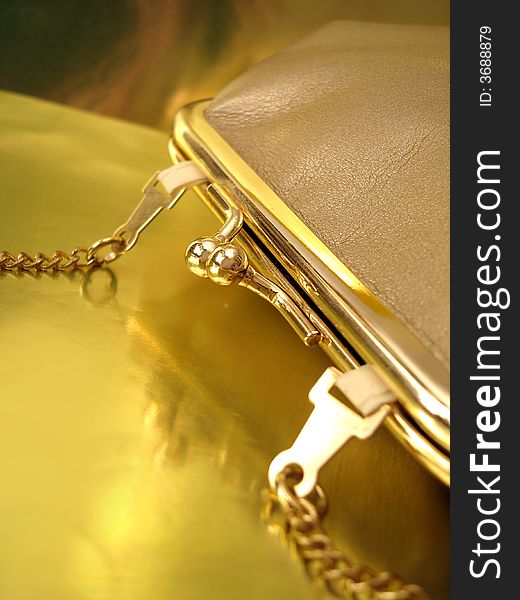 Golden womanish handbag on yellow background