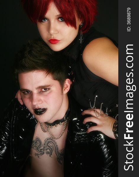 Young teen couple dressed in rocker wear over black. Young teen couple dressed in rocker wear over black.