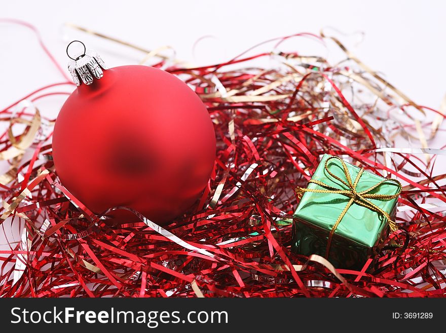 Matte red christmas ball and gift box in red tinsel.