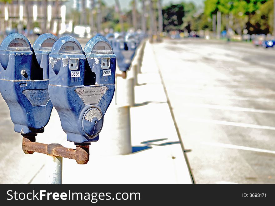 Long row of old parking meters doubled up on every rusty pole.