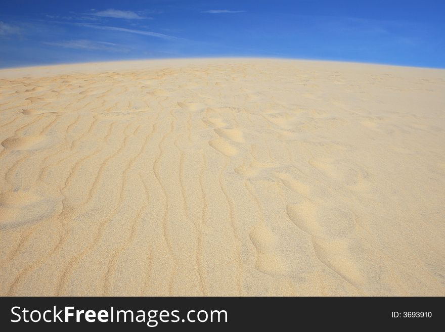 View of golden sand dunes against rich blue sky, clean versatile stock image