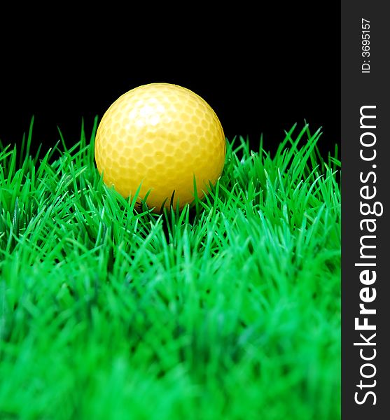 Golfball in orange tee, green fairway, isolated on black background