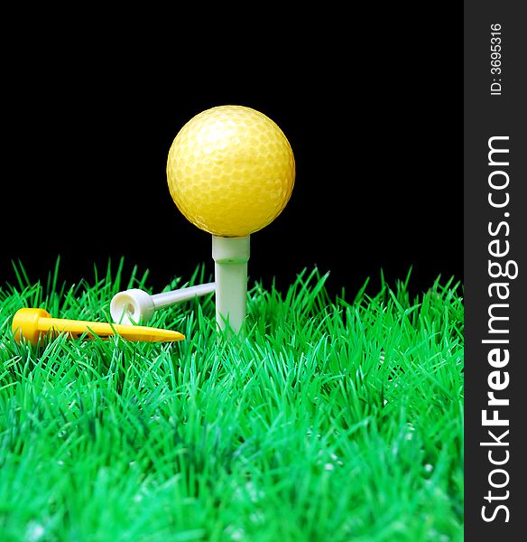 Golfball in white tee, green fairway, isolated on black background. Golfball in white tee, green fairway, isolated on black background