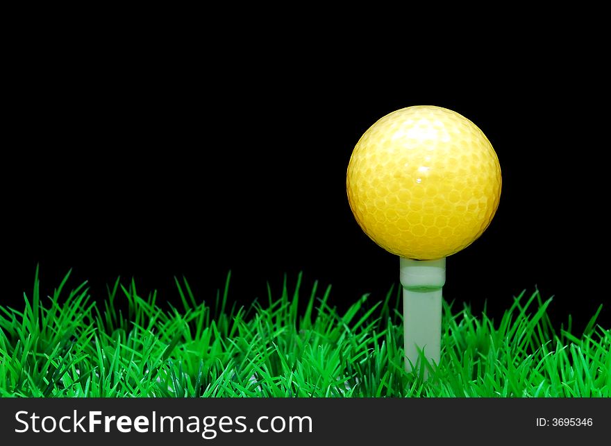 Golfball in white tee, green fairway, isolated on black background. Golfball in white tee, green fairway, isolated on black background