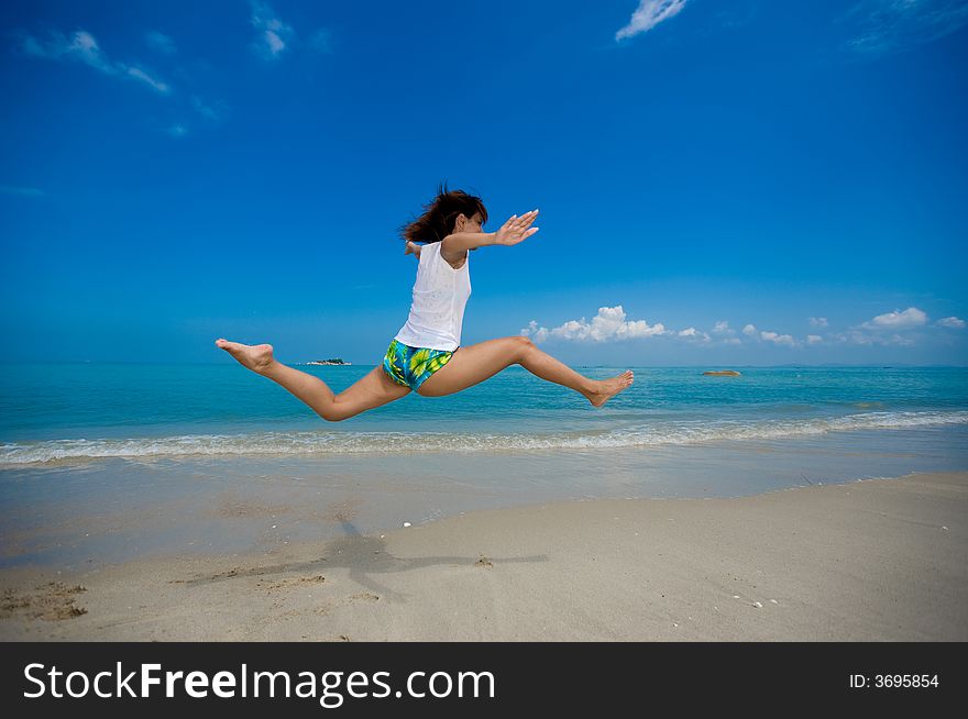 Young beautiful girl jumping happily at the beach. Young beautiful girl jumping happily at the beach