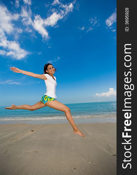 Young beautiful girl jumping happily at the beach. Young beautiful girl jumping happily at the beach