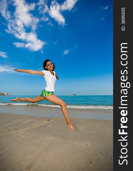 Young beautiful girl jumping happily at the beach. Young beautiful girl jumping happily at the beach