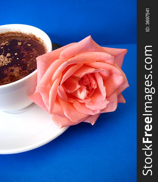 White cup of coffee with flower on blue background