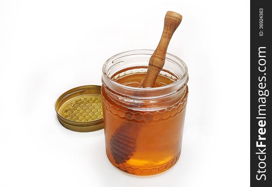 Honey glass jar with lid and wooden drizzler isolated on white background. Honey glass jar with lid and wooden drizzler isolated on white background