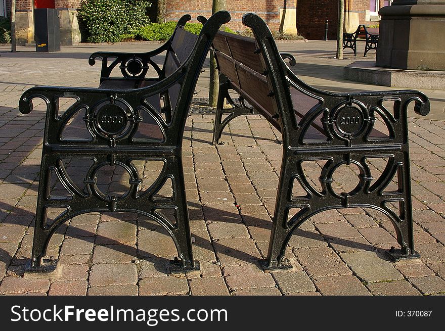 A pair of back to back public bench seats in the town square of St. Helens, Merseyside, England. A pair of back to back public bench seats in the town square of St. Helens, Merseyside, England.