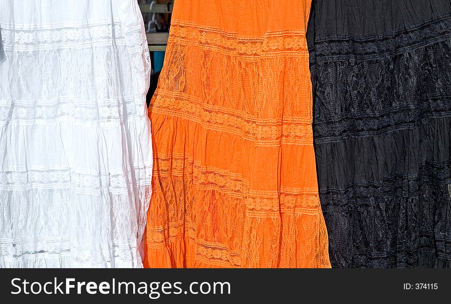 Three coloured dresses for sale at a Spanish market on the Costa del Sol. Three coloured dresses for sale at a Spanish market on the Costa del Sol