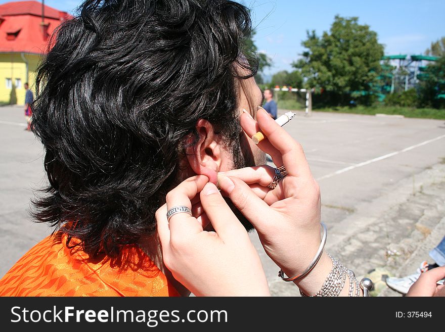 Girl piercing a boy's ear