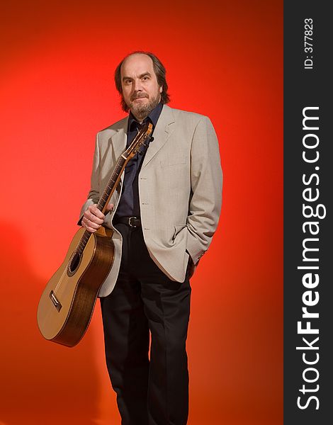 Middle aged man-musician with his guitar on a red background.