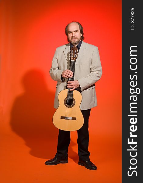 Middle aged man-musician with his guitar on a red background. Full length, with shadow.