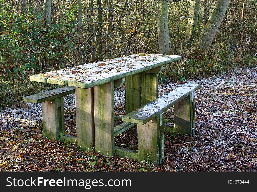 A picnic table in wooded area in winter. A picnic table in wooded area in winter