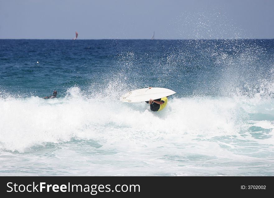 A surfer going coming out of the water - going aerial