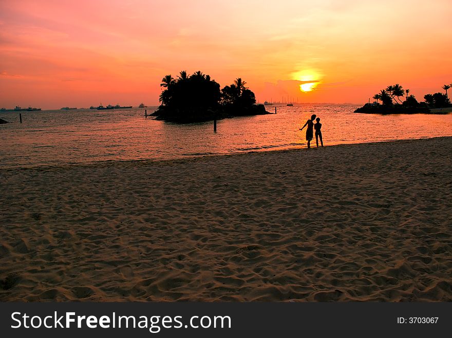 A teenager couple spending time together watching the sun set over a lagoon at a tropical island beach resort. A teenager couple spending time together watching the sun set over a lagoon at a tropical island beach resort