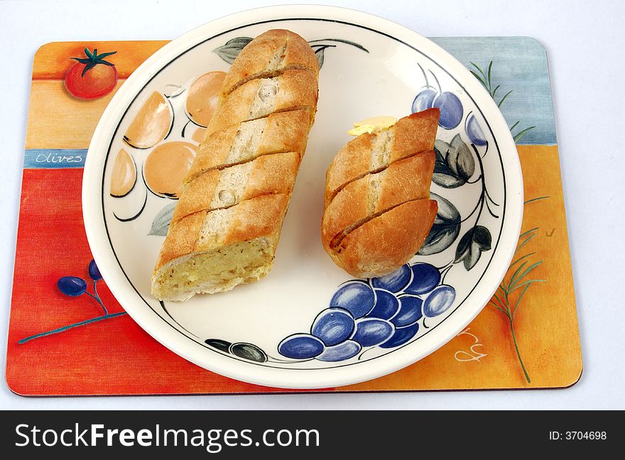 Garlic Bread on a plate on a mat.,Garlic bread is a kind of roasted or broiled bread that originates from Italy. The bread has a topping of garlic and butter or olive oil and at times even clarified butter is used.
