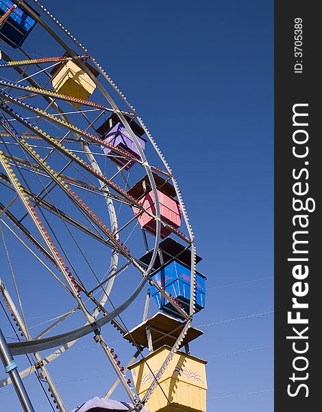 A colorful ferris wheel at a carnival against a blue sky. A colorful ferris wheel at a carnival against a blue sky