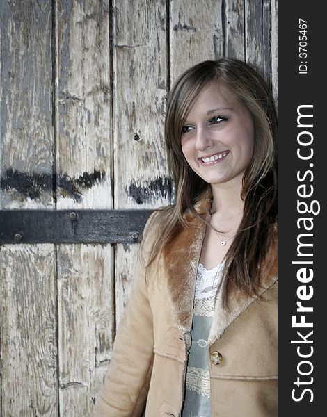 A young smiling, attractive woman with a rustic wood background. A young smiling, attractive woman with a rustic wood background