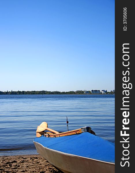 Blue canoe on the shore; blue sky