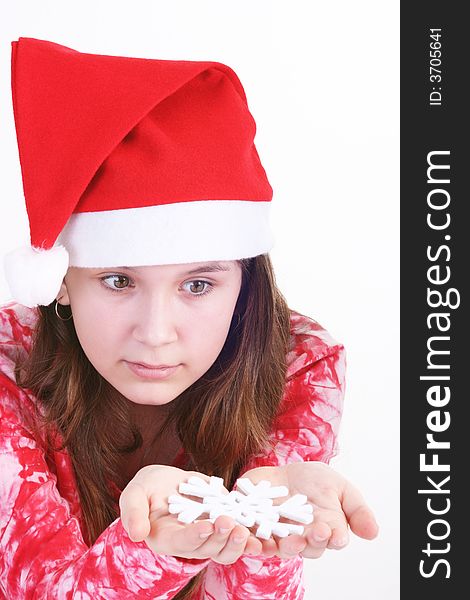 A portrait of a young teenager wearing a red Santa hat and red print top, holds out a large white snowflake in both hands in this studio setting. White background. A portrait of a young teenager wearing a red Santa hat and red print top, holds out a large white snowflake in both hands in this studio setting. White background.