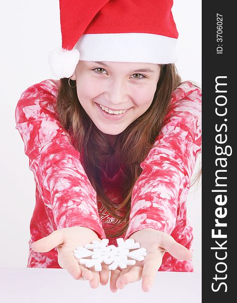 A portrait of a young teenager wearing a red Santa hat and red print top, holds out a large white snowflake in both hands in this studio setting. White background. A portrait of a young teenager wearing a red Santa hat and red print top, holds out a large white snowflake in both hands in this studio setting. White background.