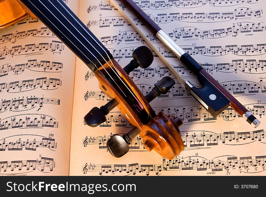 A violin and bow resting on a piece of aged classical music. A violin and bow resting on a piece of aged classical music.