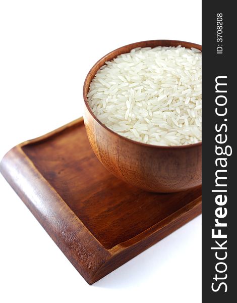 Close up picture of a wooden bowl of uncooked rice, placed on a matching wooden tray. Close up picture of a wooden bowl of uncooked rice, placed on a matching wooden tray