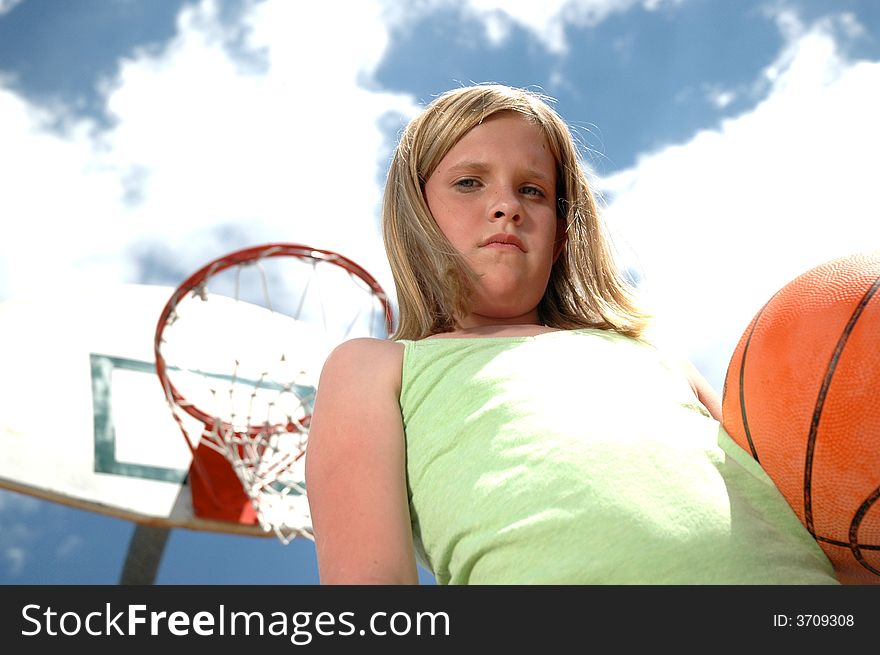 Young girl with basketball with sky and clouds