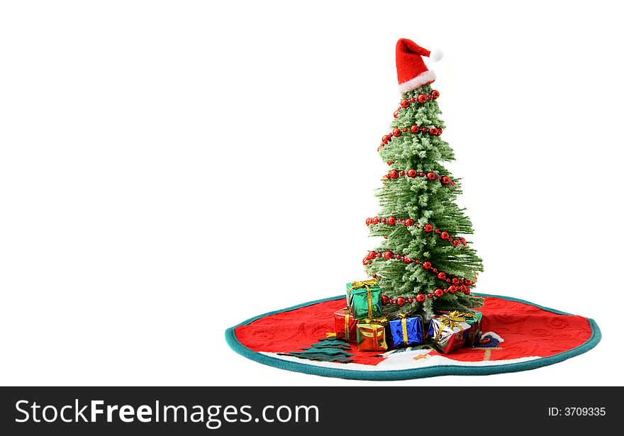 Christmas tree on red rug surrounded by gifts.