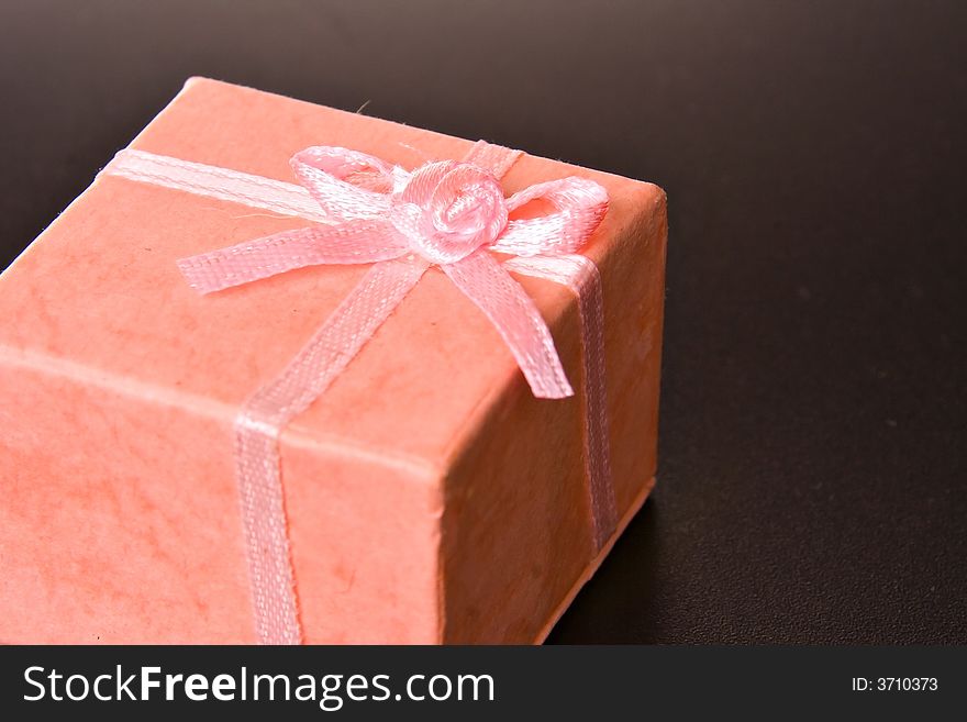 Pink gift box with ribbon on black isolated