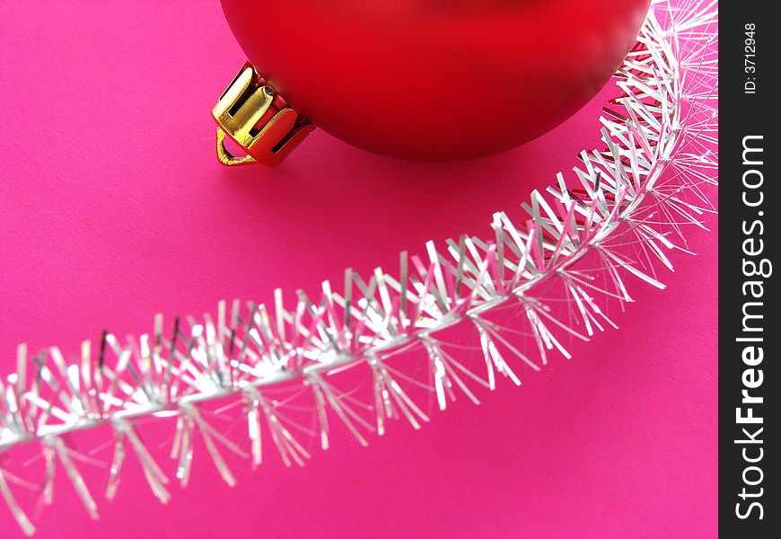 Christmas design with red bauble fragment and silver tinsel on pink background. Christmas design with red bauble fragment and silver tinsel on pink background