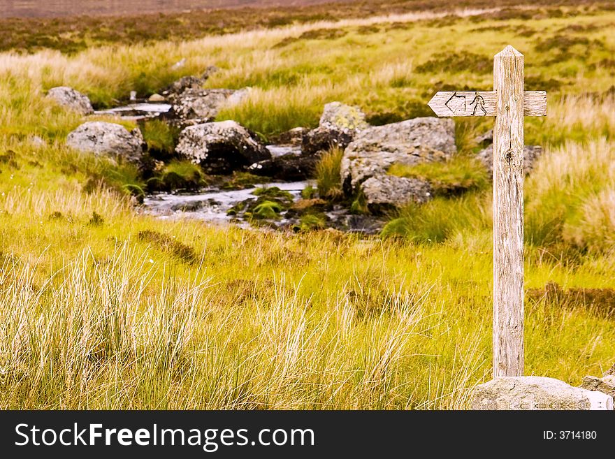 A signpost shows the way of the path in the welsh moorland grass. A signpost shows the way of the path in the welsh moorland grass