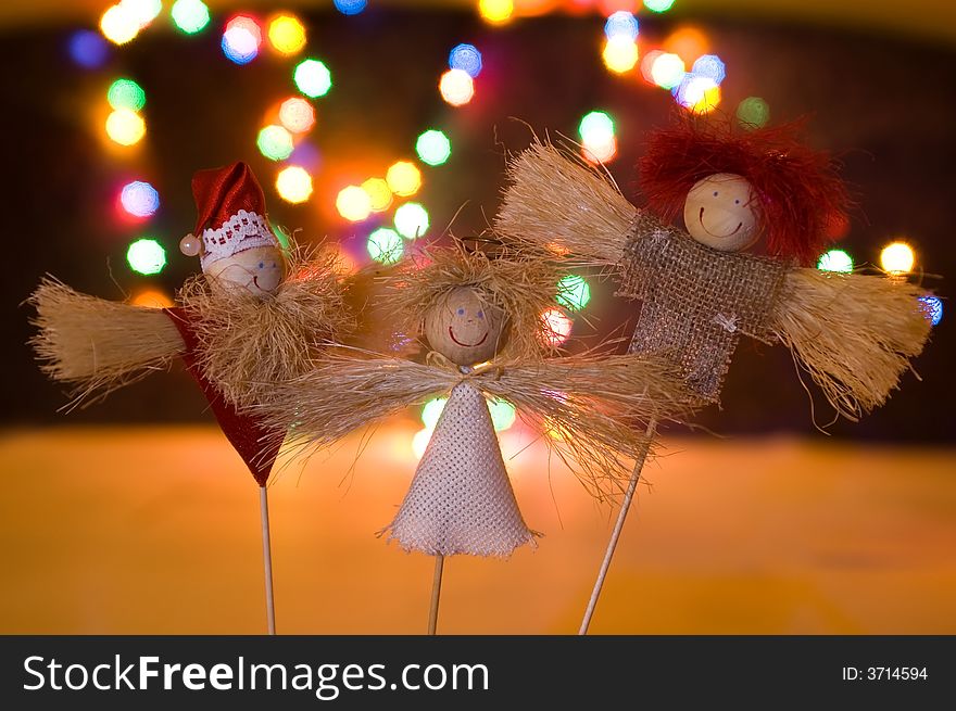 Three wooden figurines in lights of garland. Three wooden figurines in lights of garland