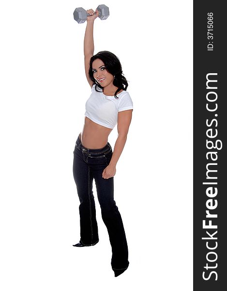 Young female personal fitness trainer in designer jeans and a half t-shirt holding a 15 pound dumbbell over her head