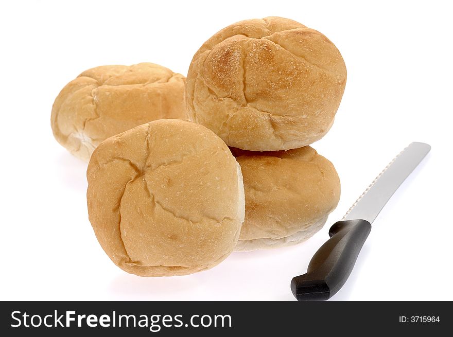 Fresh baked rolls and bread knife on white background.