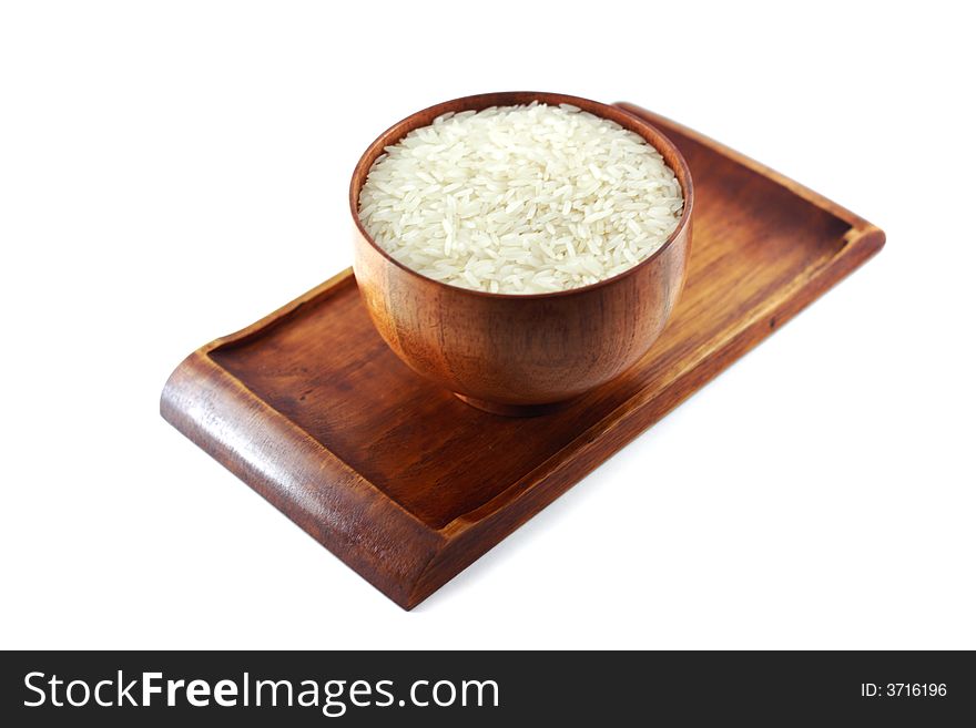 A picture of a wooden bowl of uncooked rice, placed sideways on a matching wooden tray. A picture of a wooden bowl of uncooked rice, placed sideways on a matching wooden tray.