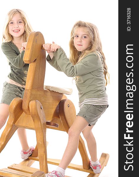 Twin children sharing a big rocking horse
