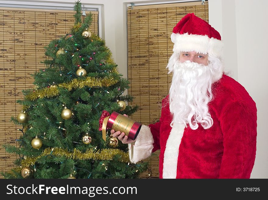 Santa Claus with gift near christmas tree. Santa Claus with gift near christmas tree