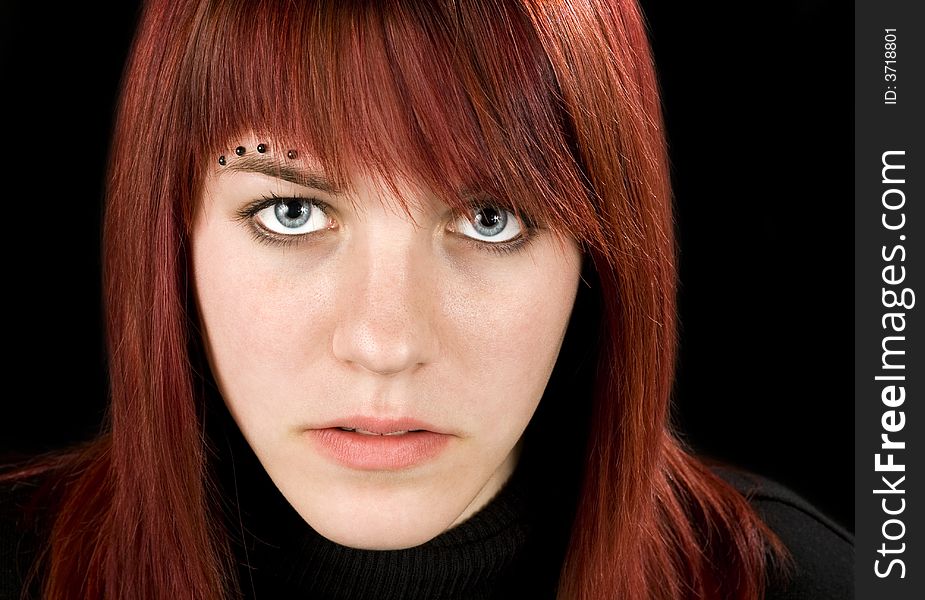 Simple frontal shot of a beautiful pierced redhead girl staring at the camera. Studio shot. Simple frontal shot of a beautiful pierced redhead girl staring at the camera. Studio shot.