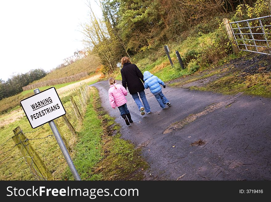 Mother and 2 children walking past a warning sign. Mother and 2 children walking past a warning sign