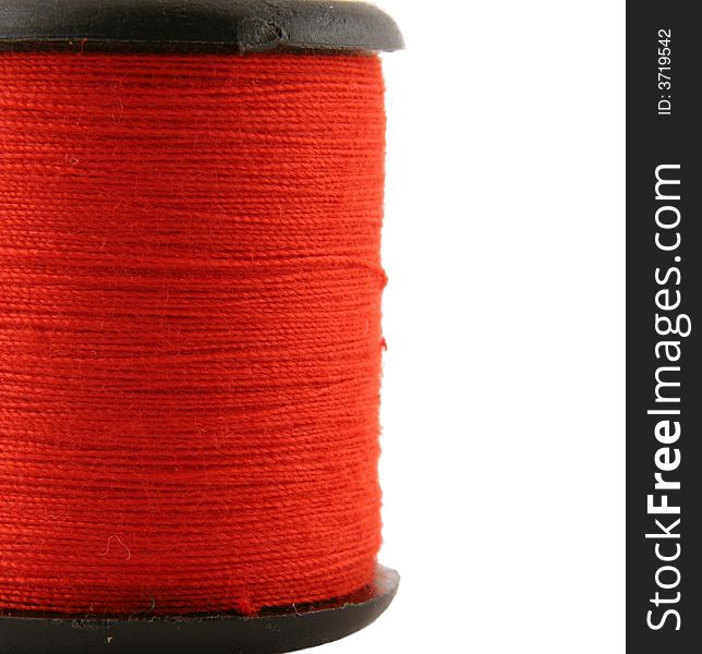 Red spool of thread over white